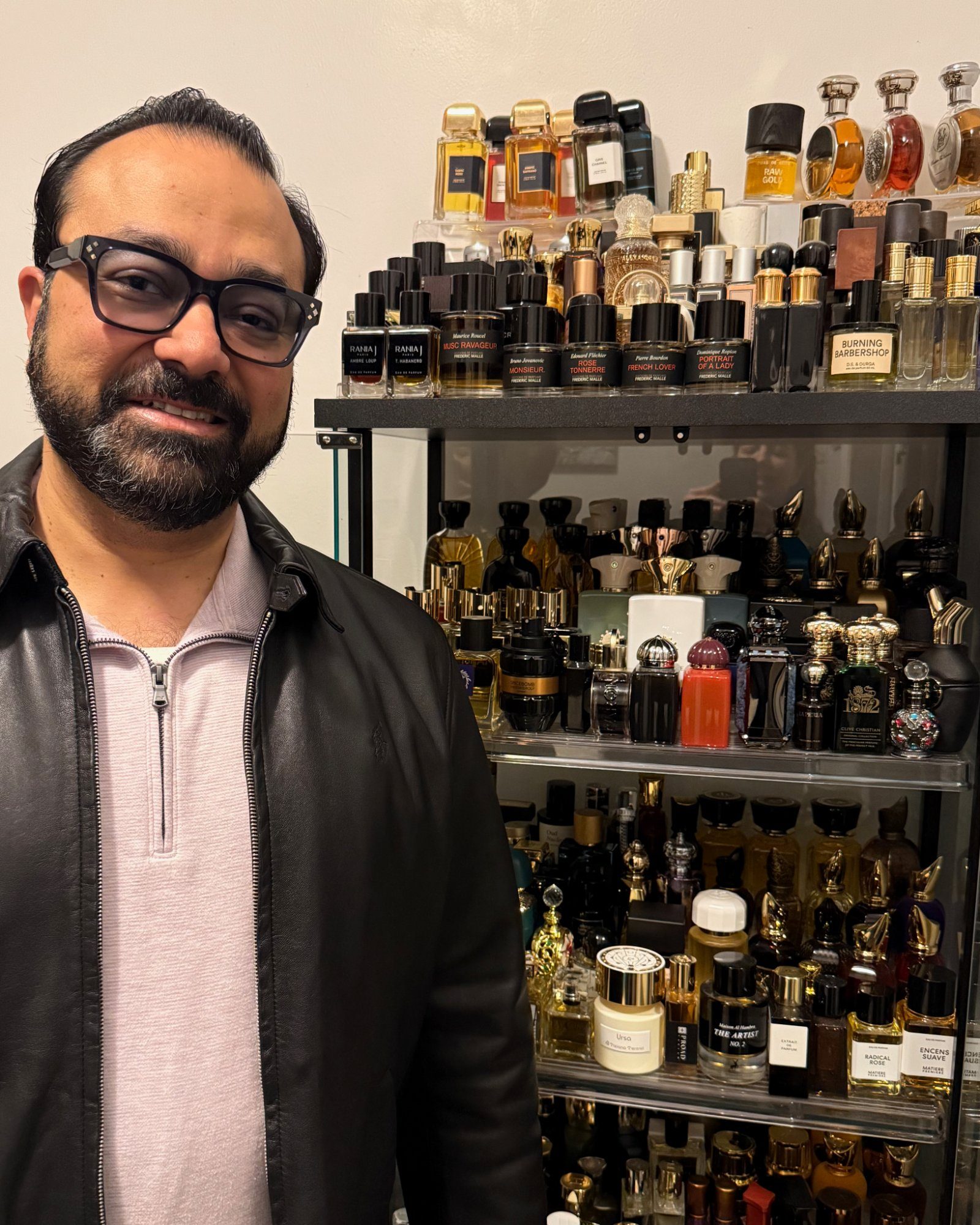 Gautam standing beside his fragrance collection of over 850 bottles including a full Frederic Malle shelf