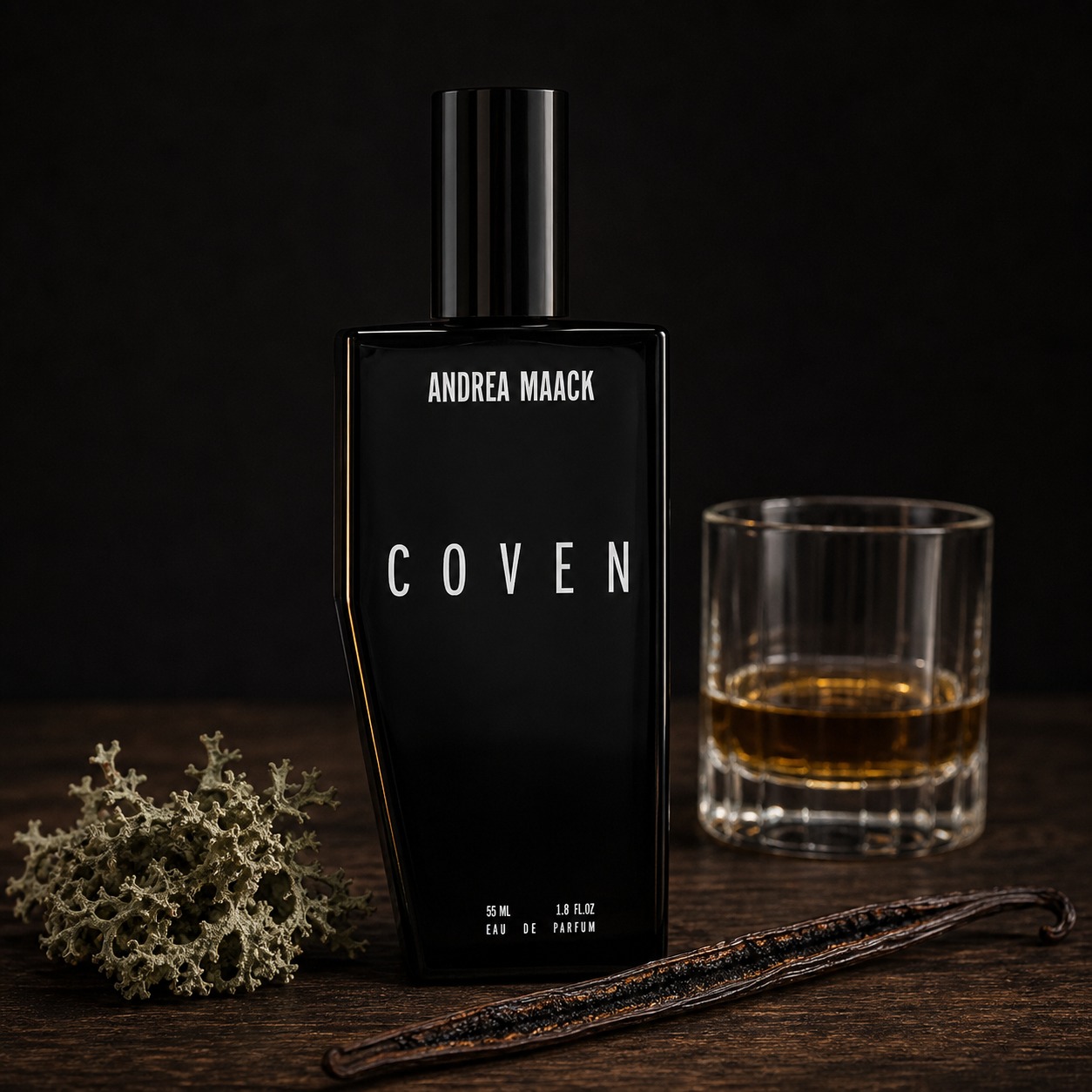 Andrea Maack Coven perfume bottle beside a vanilla pod, whiskey glass, and oakmoss